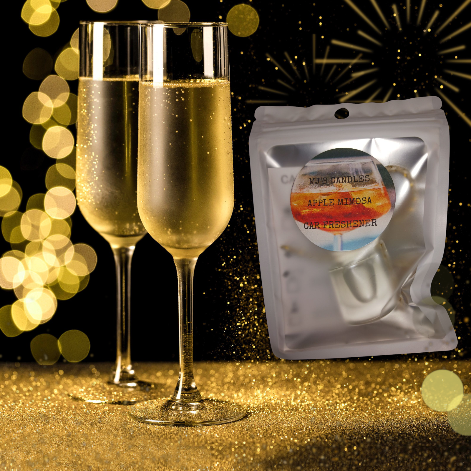 Handcrafted apple mimosa car fragrance packaged next to two filled champagne flutes with gold glitter background