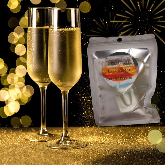 Handcrafted apple mimosa car fragrance packaged next to two filled champagne flutes with gold glitter background