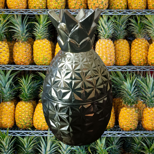 Luxury natural soy candle 7oz in a metallic pineapple-shaped container against a background of fresh pineapples