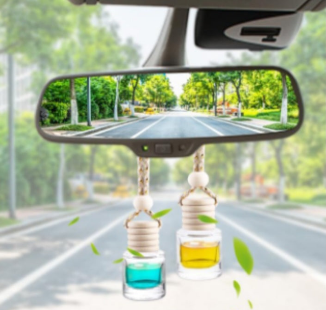 Lavender and honey car freshener hanging from rearview mirror inside a car with green leaves
