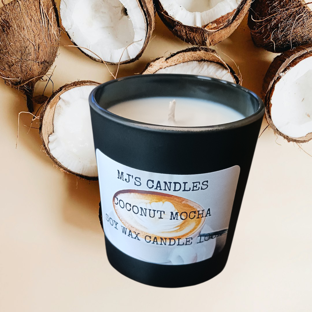 Handcrafted coconut coffee candle by MJ'S CANDLES LLC in black jar surrounded by coconut shells