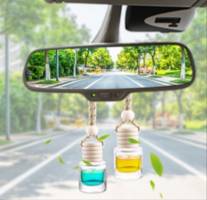 Handcrafted fruit scented car freshener hanging from rearview mirror with green leaves around