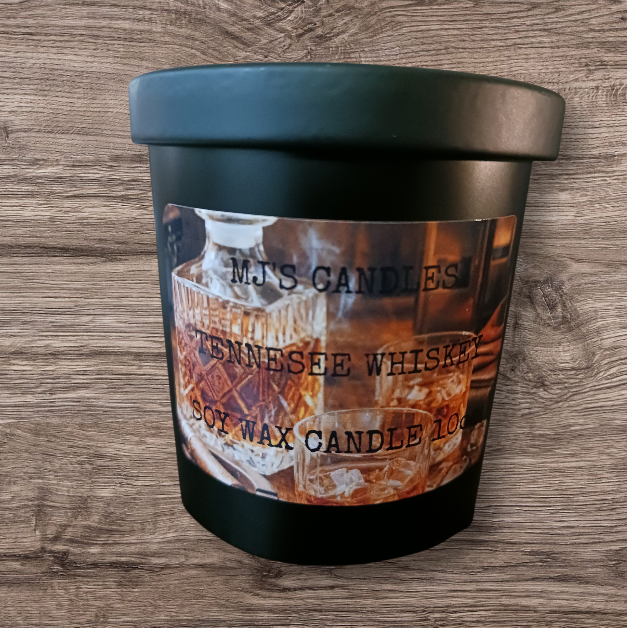 MJ'S CANDLES black jar soy wax candle with Tennessee whiskey label on wooden surface